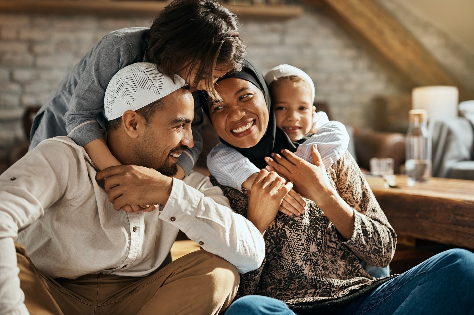 Happy Muslim kids embracing their parents and having fun at home.